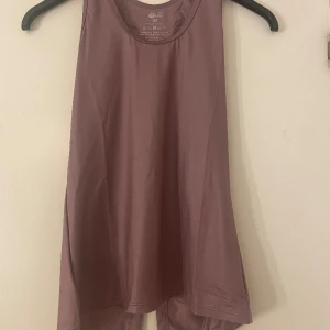 Tränings linne  - Helt oanvänt tränings linne. Linnet har en slit i ryggen och är i en fin lila färg. Packas i original påsen.