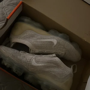 Vapormax 2021 - De är använda men fortfarande i bra skick. Snörerna kan stoppas tillbaka. Det finns ett litet hål i hälen som gör ett litet ljud när man går. Annars funkar de perfekt.