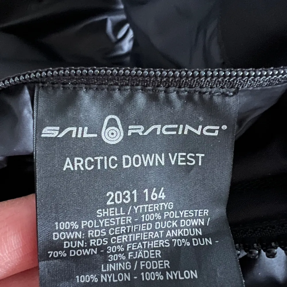 En svart väst i dun med huva från Sail racing i mycket bra skick. Använd en handfull gånger.  (Sail racing arctic down vest) . Jackor.