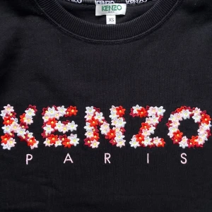 Svart KENZO-sweater med blommig logga - Den PERFEKTA vår- och sommartröjan! Materialet är ett lite hårdare bomullstyg, vilket ger en lyxig känsla. Sweatern är i storlek XS, men passar S om man vill ha den tajtare. Använd sparsamt, därav mycket bra skick. Slutsåld modell. 