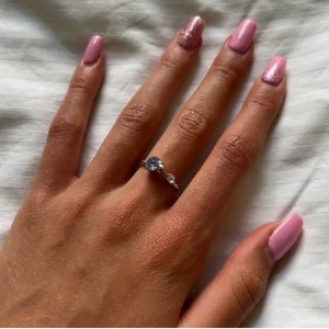 Caroline svedbom ring - Nani ring med blå Sten som ej säljs längre. Använd fåtal gånger så i bra skick. Har tyvärr slängt asken så ringen kommer skickas i en annan ringask. Passar alla storlekar. Nypris 395kr