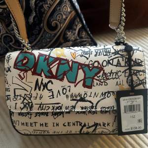 Jag säljer en helt ny DKNY axelremsväska! Den har fortfarande prislappen kvar och är modern och häftig. Den rymmer mycket och finns i Huddinge, men kan även skickas per post (köparen står för frakten). Jag köpte den för 158 dollar.