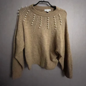 Stickad tröja - Detta är en stickad tröja med pärlor på bröstet! Tröjan är beige och mycket mjuk i materialet😀💗 Den är i storlek S och har inga skavanker!  Hör av dig ifall du har några frågor!😊