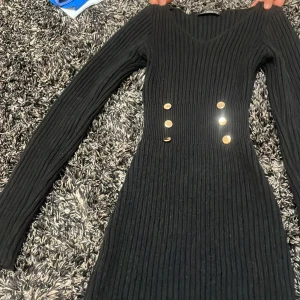 Stickad kläning med guld ringde på magen  - Super fin och mjuk med en lätt v ringning