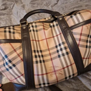 Burberry skötväska - Material: 100% Polyvinyl/ 100% bomull/ 100% läder  Färg: Beige/brun  Skick: Använt/bra skick!   Väskan har fyra stor fack på insidan. Där du kan organisera både blöjor, nappflaskor, nappar och andra nödvändighete  Köptes 2018 från butiken Affordable