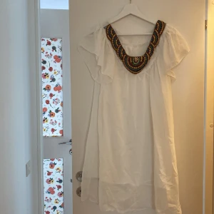 Vit klänning med pärlor vid halsen  - Fin skön vit klänning med detaljer av pärlor vid halsen.