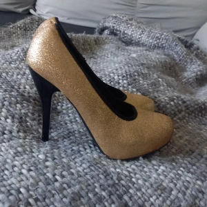 Guld-Glitter Pumps - Fest pumps använda ca 3 gånger. Några slitage finns (bild 3) kommer mestadels från att legat bland andra skor.  Dem ska vara storlek 39 men skulle säga storlek 38.5