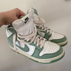 Nike Dunk High 1985 - St 38,5 men smal i skon. Använd fåtal gånger så bra skick. Vitt läder med mintgrön denim.