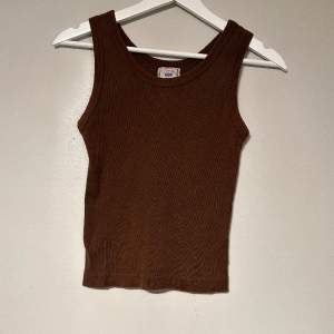 Ett brunt ribbat vintage linne i storlek S. Tröjan har breda axelband och är normal i längden. Tröjan är i mycket bra skick då den nästan aldrig kommit till användning. 