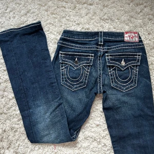 Lågmidjade Bootcut jeans true religion  - Superfina, lågmidjade &bootcut. Jätte fint skick, enda ”defekten” är en av knapparna där bak-märks inte/ lätt att fixa. Innerbenslängd:80 midjemått: 37+ stretch. Vill du köpa trycker du på köp nu, jag postar inom 24h