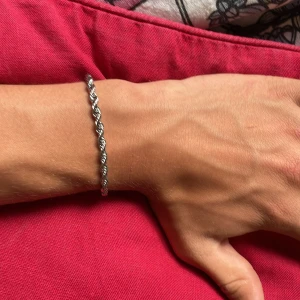 Kedjearmband i rostfritt stål - Vriden kedje armband i oanvänt skick i rostfritt stål. Mått:18cm Kan stå för frakten om de köps innan 2 juli