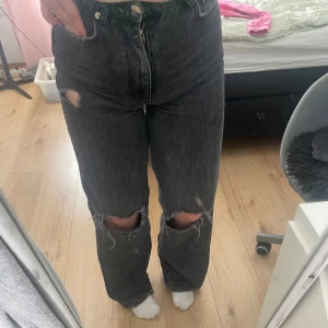 Högmidjade jeans - Coola hägmidjade jeans med hål på båda knäna och ett på vänster lår.