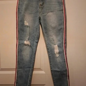 Nya ankle jeans  - Helt nya jeans i ankle höjd. Fina slitningar och ett rött och vitt band längst sidan av benen. Kommer från ett djur och rökfritt hem 