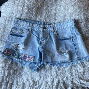 Low waist ljusa jeansshorts med broderi - Ljusa low waist jeansshorts i bra skick med broderi på