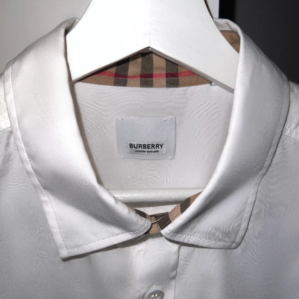 Storlek L, använd en gång. Tillverkad av 100% bomull, har denna skjorta en optisk vit rutig tryck, en klassisk krage och en knappknäppning framtill. De långa ärmarna med knappade manschetter och den böjda fållen ger en touch av sofistikering till den. Skjortor.