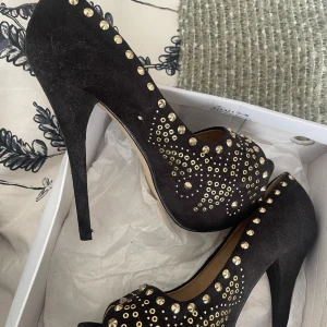 Klackskor med guld detaljer  - Klackskor med platå öppen tå med gulddetaljer,  knappt använda med minimalt slitage på sulan. De är ganska höga 10 cm minst 