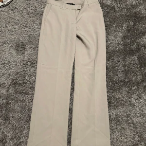Beige kostymbyxor - Kostymbyxor som inte kommer till användning då dom är förstora. Endast använda 1 gång.