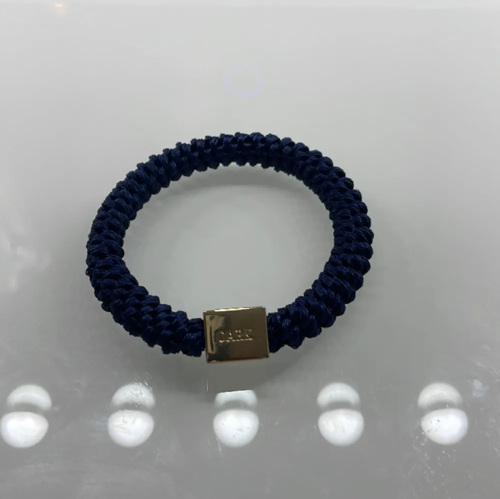 Marinblå snodd/armband med en liten gulddekor. Accessoarer.