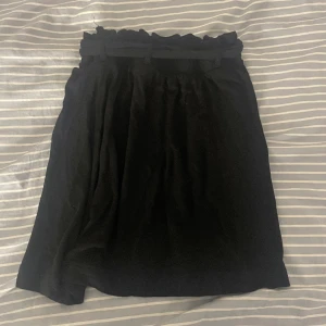 Kjol - En vanlig svart kjol med ett tyg ”skärp” som jag på bilden knutit bakom ryggen.