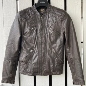 Snygg mörkbrun skinnjacka  - Snygg skinnjacka i mörkbrunt, mjukt skinn.  Storlek 36. Mörkbrunt foder. Fyra fickor med dragkedja framtill och en innerficka med dragkedja. Mycket lite använd. 