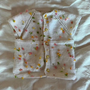 Stickad Vintage Baby topp XS - En stickad vintage babytopp med blommor. Kan bäras som cropptop i strl XS!   Köparen står för frakten!