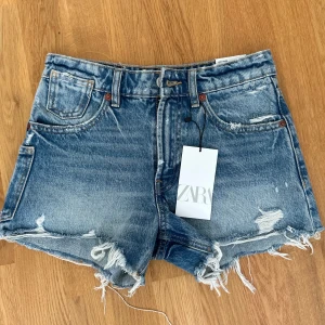 Zara jeans shorts - Säljer ett par superfina jeans shorts ifrån ZARA. Dem heter ”High-Rise Frayed”, men skulle säga att dem är medelhöga i midjan. Dem är endast testade och har lappen kvar, men säljer för att de inte passade. Storlek:34. Nypris:300kr. Säljer för: 155kr!