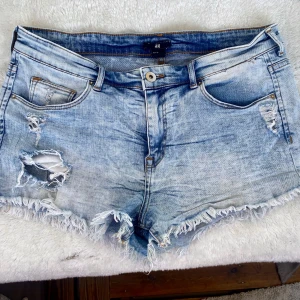 Jeansshorts  - Ljusa jeansshorts i storlek 40. Ganska lågmidjade, slitningar fram och även ena fickan bak. Ganska stretchiga 