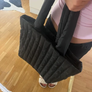 Väska - Svart väska i dunmaterial. Köpt på hm!! Säljer då jag har för många väskor. Hör av dig vid frågor<3