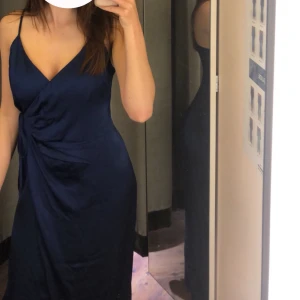 Mörkblå satin klänning från bikbok  - En nästan oanvänd satin klänning från bikbok. Endast använd en gång på ett bröllop ser ut som nyskick.  Säljer pga att den blivit för liten i bysten.  Nypris 450 kr, säljer för 200kr. 