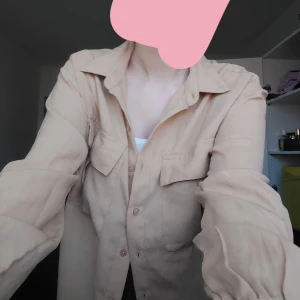 Skjorta trendig - Kan stylas på klänningar, jeans. Beige färgad och storlek är S. Trendigt just nu med skjorta över maxikjol. Jag samlar pengar till min brors student så kontakta mig snabbt om ni vill köpa