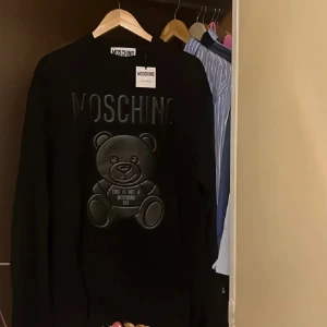 Moschino black teffy Sweat - En oanvänd Moschino tröja i storlek 52( passar jättebra som en oversize för en med storlek S/M) Köpt från Nk i Göteborg för 4299kr. Den originala förpackning samt kvitto finns. 