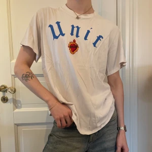 vit T-shirt graphic tee UNIF broderat gotisk vintage - Vit t-shirt / graphic tee från UNIF med deras logga i blå gotisk font och ett broderat brinnande hjärta🔥🫀SÅ skönt och en elevated basic ⭐️