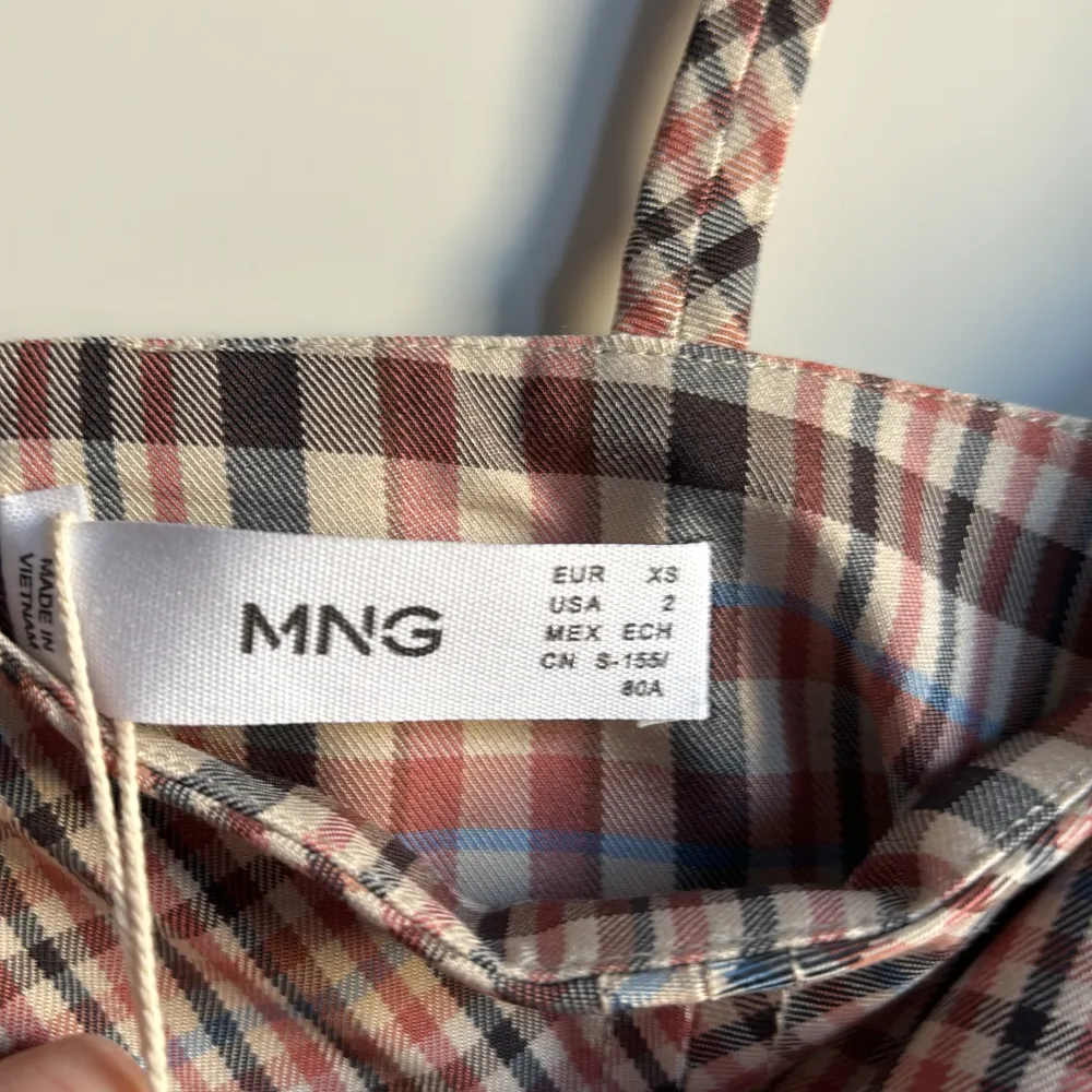 Rutig klänning med tunna axelband och dragkedja i ryggen. Köpt från Mango. Mycket skönt material med 60 % viskos, 38 % polyester och 2 % elastan. Innerklänning/foder i 100 % polyester. Aldrig använd!. Klänningar.