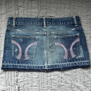 Jeanskjol - Y2K, går inte att få tag på längre!!! Helt ny med lappen kvar. Storlek 3 (25/26?), 100% bomull. Midjemått 78 cm, framsidans längd 27 cm, baksidans längd 29 cm. Priset går inte att diskutera, använd gärna KÖP NU.