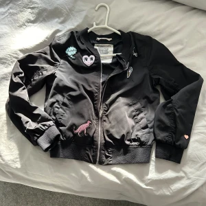 Bomberjacka flick  - Svart bomberjacka med brodyr. Använd men i bra skick.