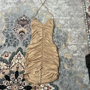 Klänning - Beige ”scrunchad” klänning, med öppen rygg, som man kyter runt halsen❤️ Formar kroppen snyggt! Nyskick!