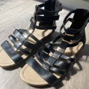 Sandaler - Fina sommar sandaler med guldiga detaljer, dragkedja på baksidan. Knappt använda, säljes pga att dom är för små