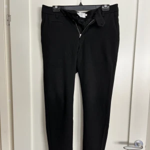 Les Deux - Como suit pants black - ”Les Deux kostymbyxor Como Suit i svart har en snygg, smal passform och är enkelt dekorerade med upprullade fållar och en ton-i-ton broderad Encore-logo på baksidan.” Nypris 1100kr. Bra skick. En söm har släppt, (bild) men syns ej när dom sitter på.