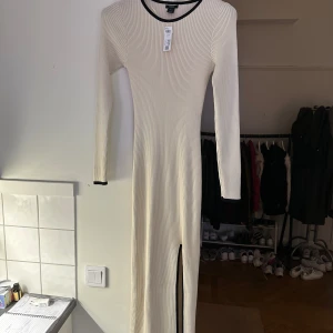 Stickad klänning  - Ribbstickad, figurnära klänning med långa ärmar och en slits på framsidan.  Långa ärmar Midi-längd Gjord i 77% LENZING™ ECOVERO™ viskos Längd: 132 cm i storlek M Skötselråd Maskintvätt 30° skontvätt Kan krympa 3-5% Material 77% viskos 23% polyester 