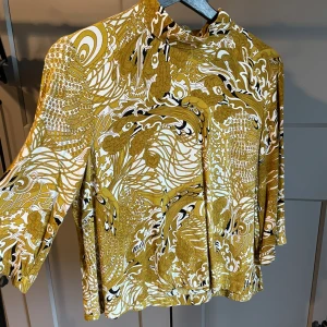 Mönstrad blus - Mönstrad blus i ockragul. Sparsamt använd. Kortare i modellen. Dragkedja i nacken.