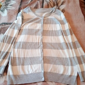 Kofta randig vit och grå med knappar.M/L - Kofta randig vit och grå stl M/L med knappar.