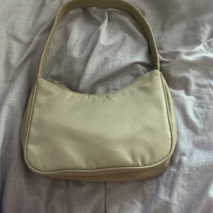 Baguette väska - Säljer denna väska. Använder inte längre därför säljer jag den. Väskan har en beige färg och är inte så stor men rymmer mycket. Min parfym får plats som är ganska stor. Säljer väldigt billigt för 50kr 
