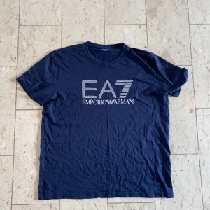 Emporio Armani T-Shirt i Storlek L - En Emporio Armani T-shirt i storlek L🔥Fint skick och även fast den är i storlek XXL så är den otroligt liten i storlek och därav L, men kontakta gärna för mått eller andra frågor🔔
