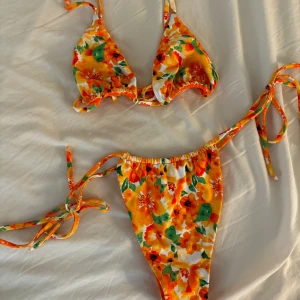 Bikini från FL swimwear - Bikini från FL Swimwear. Överdelen är i modellen hawaii top och underdelen är i modellen amore bottom. Har även bifogat bilder på hur modellerna ser ut, men den jag säljer är orange blommig.   Storlek S i båda. Köptes för 849 kr styck.