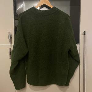Stickad tröja från H&M i mossgrön fin färg. Tröjan är märkt i storlek xs och oversize modell. Inga hål men lite uppkomst till noppor (se bild tre för exempel) och är i använt skick.