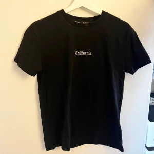 T-shirt med tryck på ryggen - En svart t-shirt med tryck på ryggen. Strl XS, men stor i storleken!