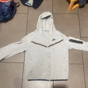 Nike tech fleece - Nike tech fleece i färgen grå. Skicket är  7/10 då det är en liten slitning på vänster arm nere vid handen.