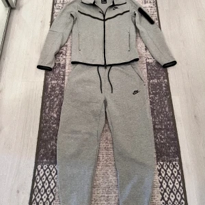 Nike tech fleece GRÅ - Säljer en jätte fin grå nike tech flecce koftan är storlek XS och byxorna M, byxorna är i nytt skick men koftan är i använt skick, inga synliga deffekter på koftan, vid frågor eller funderingar är det bara att höra av er!
