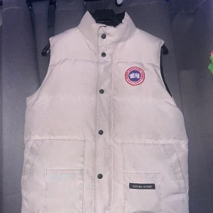 Canada Goose väst  - Säljer nu min vita Kanada Gosse väst då jag tröttnat och är sugen på nått annat , det är storlek M men kan även passa S. Är du intresserad eller vill ha fler bilder är de vara att skriva 
