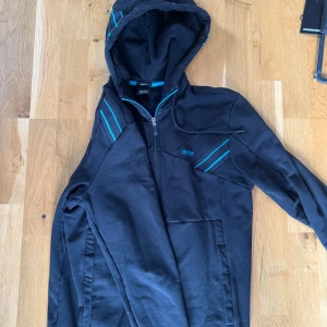 Hugo boss huvtröja - storlek S - Väldigt stilren Hugo Boss hoodie med simpla färger som blir lätt att matcha med andra plagg. Hänger i gaderob för den ej passar därav säljs den. Använt skick. Retail 1699.